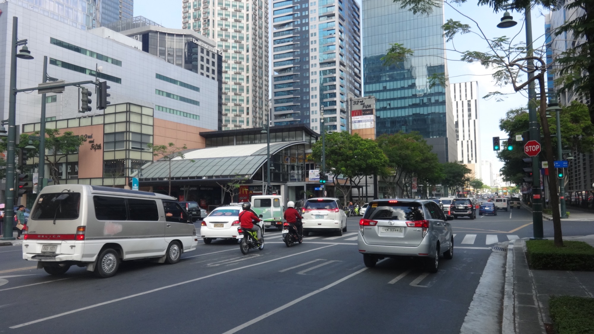 Morning traffic on 32nd Avenue in Bonifacio Global City, Taguig, with office towers behind the intersection
